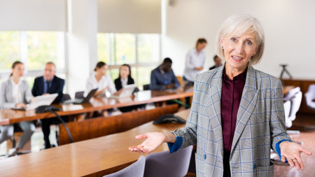 Portrait of an elderly successful businesswoman in meeting room against the backdrop of team of her colleaguesの写真素材