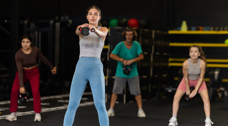 Sportive young woman lifting heavy kettlebell in sports hallの写真素材