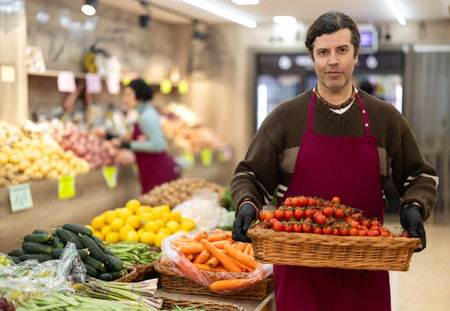 Adult man seller with basket of cherry tomatoesの写真素材