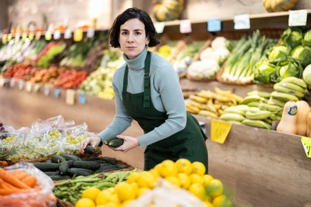 Woman shop seller puts cucumber goods on display caseの写真素材