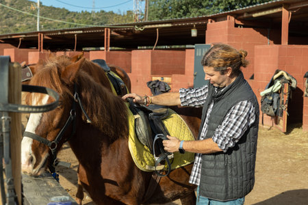 Positive man invites to ride horse at horse farmの写真素材