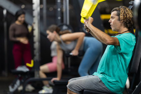 man performs a shoulder press while sitting in a machineの写真素材