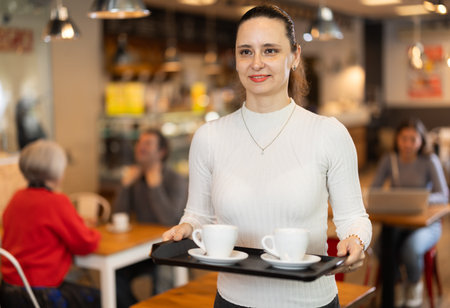 Breakfast in cafe - woman carries tray with two cups of coffeeの写真素材