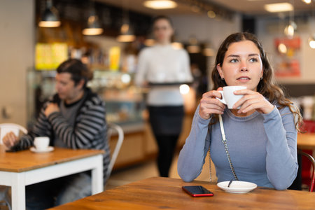 Girl whiles away time and waits for meeting in chain cafeの写真素材