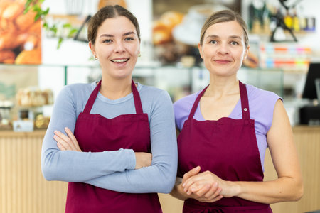 Two polite waitresses welcome clients in cafeteriaの写真素材