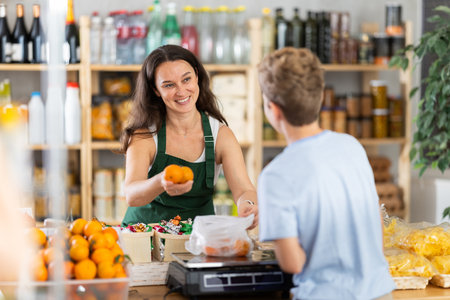 Teenage boy buys tangerines. Female seller weighs tangerines on scalesの写真素材