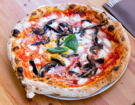 Pizza with melted cheese, ham, mushrooms and greensの写真素材