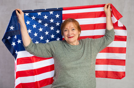 Cheerful senior woman holding national flag of United Statesの写真素材