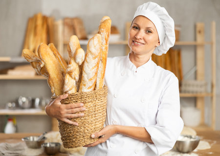 Female baker worker shows many products baguettes