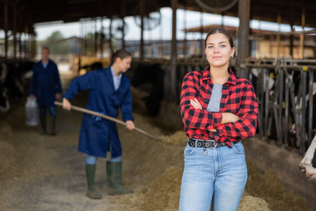 Positive young woman farmer in cowshed