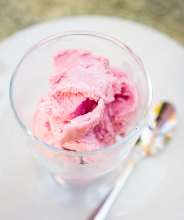 Serving of strawberry ice cream is perform in clear glass cupの写真素材