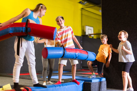 Children having funny wrestling by inflatable logs in indoor amusement parkの写真素材