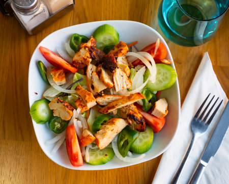 Grilled chicken salad with cucumber, padron pepper, tomatoes, onionの写真素材
