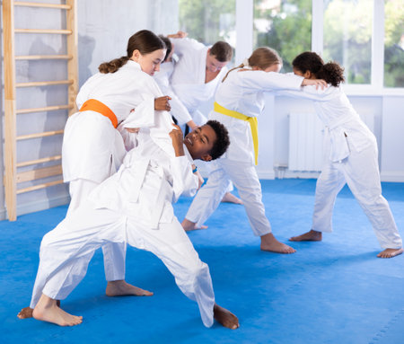 Teenage girl practicing fighting techniques during martial arts sparring with boyの写真素材