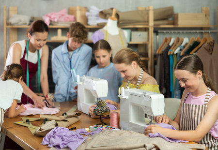 Teenage girl working at machine during group sewing course for school childrenの写真素材