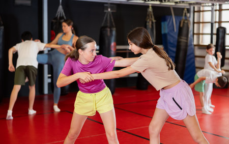 Purposeful engrossed teen girls train during self-defense fight training session in gymの写真素材