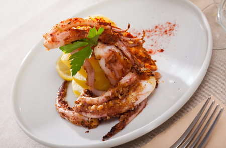 Delicious cooked squid or octopus tentacles with lemon and parsley on a plate