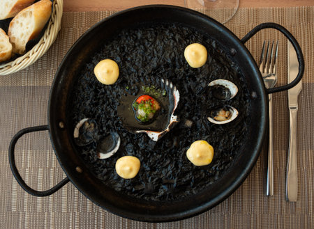 Paella is variant of dish made from black rice and seafoodの写真素材