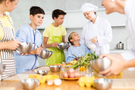 During cooking class, teenage boy stands on other side of table from male cook and looks at himの写真素材
