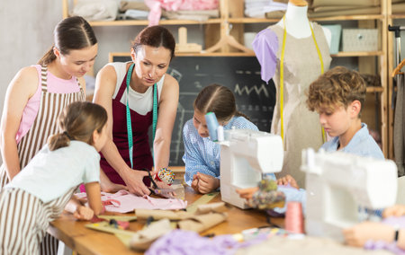 Seamstress demonstrating fabric cutting during sewing class for teenagersの写真素材