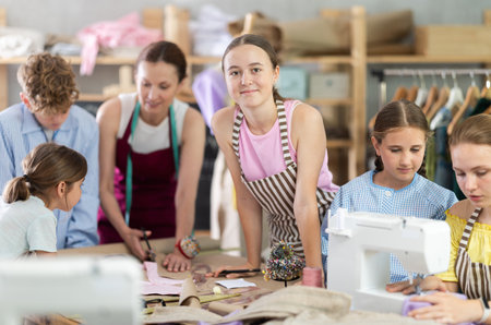 Sewing lesson - a group of teenage children learn to sew on sewing machine and cut fabricの写真素材