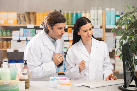 Two pharmacists searching for information on the internet together in pharmacy interiorの写真素材