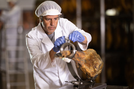 Man factory worker places hamon in cutting device jamonero