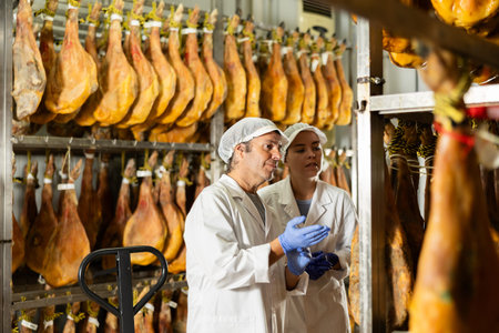 Two workers in the ham maturation shop discussing quality
