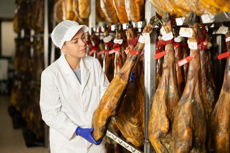 Girl checks quality of spanish jamon in workshopの写真素材