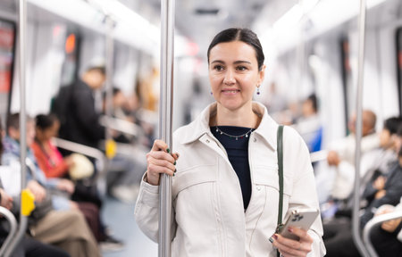 Woman with phone stand in metro carriage.の写真素材
