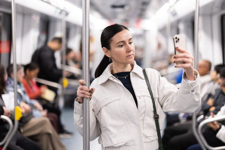 In the subway car, woman with mobile phone makes a selfie or scans QR code
