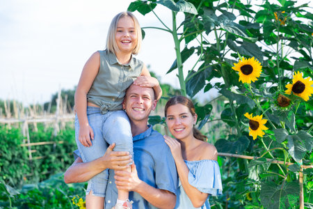 Family in the garden. Father holding little daughter on shoulderの写真素材