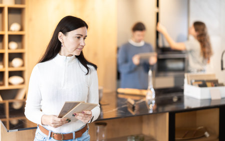 Female shopper carefully selects samples of material for a future kitchen set in furniture storeの写真素材