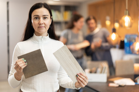 Female shopper carefully selects samples of material for a future kitchen set in furniture storeの写真素材
