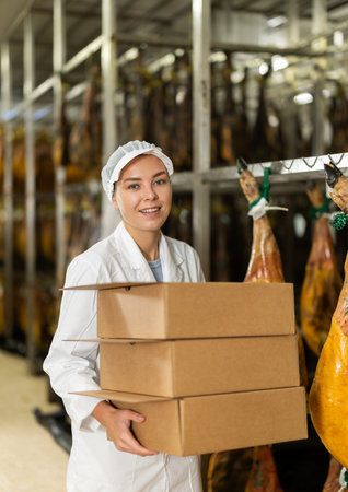 In factory department, worker carries cardboard boxesの写真素材