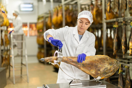 Woman places jamon on jamonero to cut it into appetizing pieces. Ham factoryの写真素材
