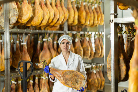 In jamon production shop, woman employee demonstrates final productの写真素材