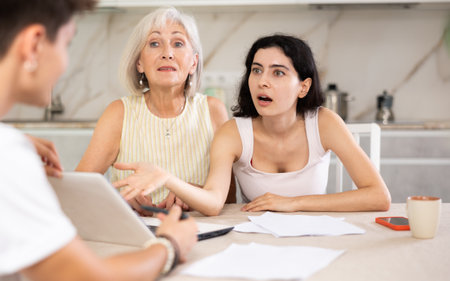 Elderly and young female clients listen attentively and intently to male sellerの写真素材