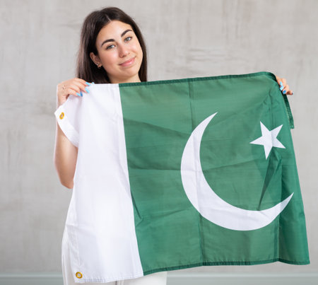 Happy young woman with flag of Pakistan against unicoloured backgroundの写真素材