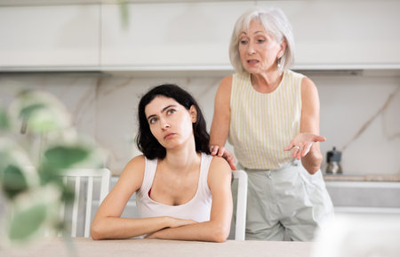 Aggrieved elderly woman having quarrel with her daughter at home. Mature mother expresses claims to adult daughterの写真素材