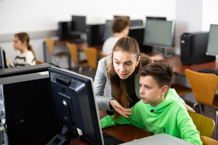 Teacher explaining task solution to pupil during computer science lessonの写真素材