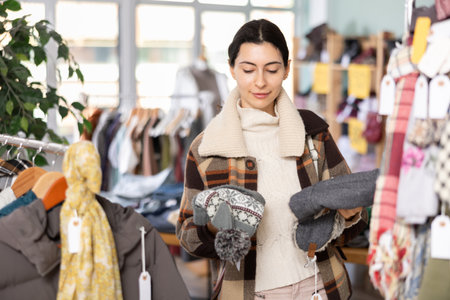 Woman chooses a warm hat for the winter in the storeの写真素材