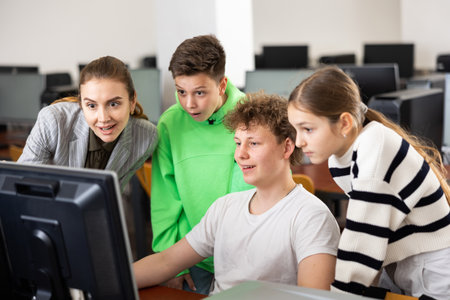Female teacher helping schoolboy and schoo lgirl in computer classの写真素材