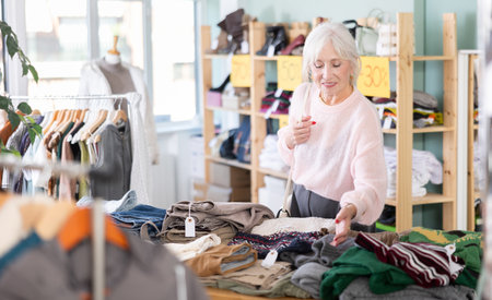 Regular customer senior woman chooses color and style of sweaterの写真素材