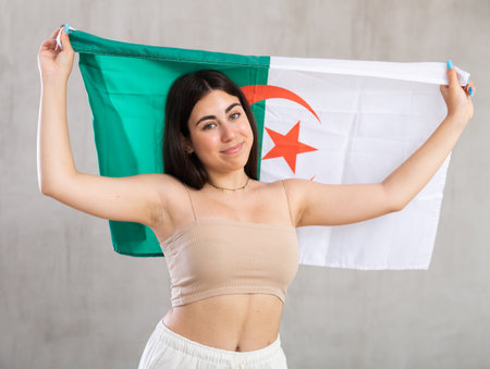 Happy young woman with flag of Algeria against unicoloured backgroundの写真素材