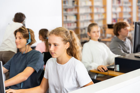 Young boys and girls using computers in libraryの写真素材