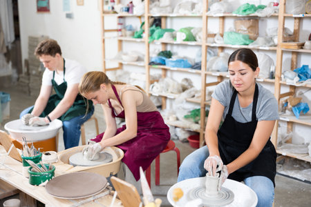 Pottery master together with students create pottery on a potters wheel in workshopの写真素材
