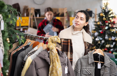 Young Armenian girl choosing coat in clothing storeの写真素材
