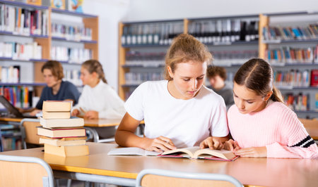 Two schoolgirls take notes in a exercise book of the necessary material from the textbookの写真素材