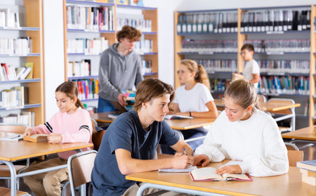 Teenage boys and girls in libraryの写真素材